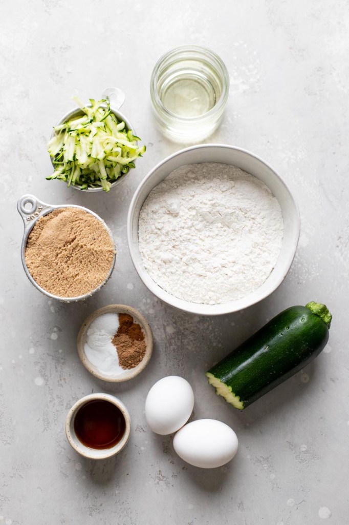 An overhead view of the ingredients needed to make homemade zucchini muffins. 