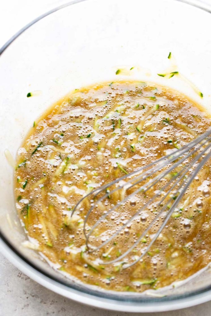 An overhead view of the wet ingredients for zucchini bread muffins in a mixing bowl.